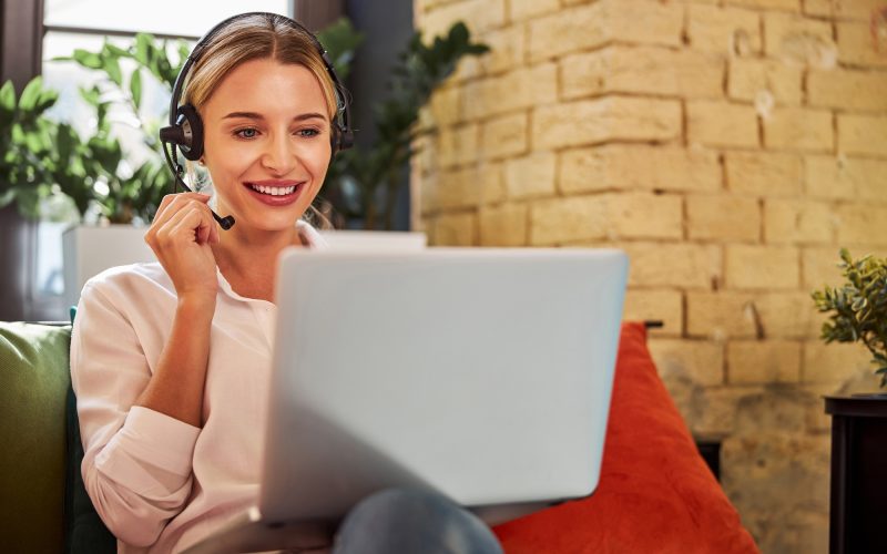 Charming business lady in headphones talking with business partner on laptop